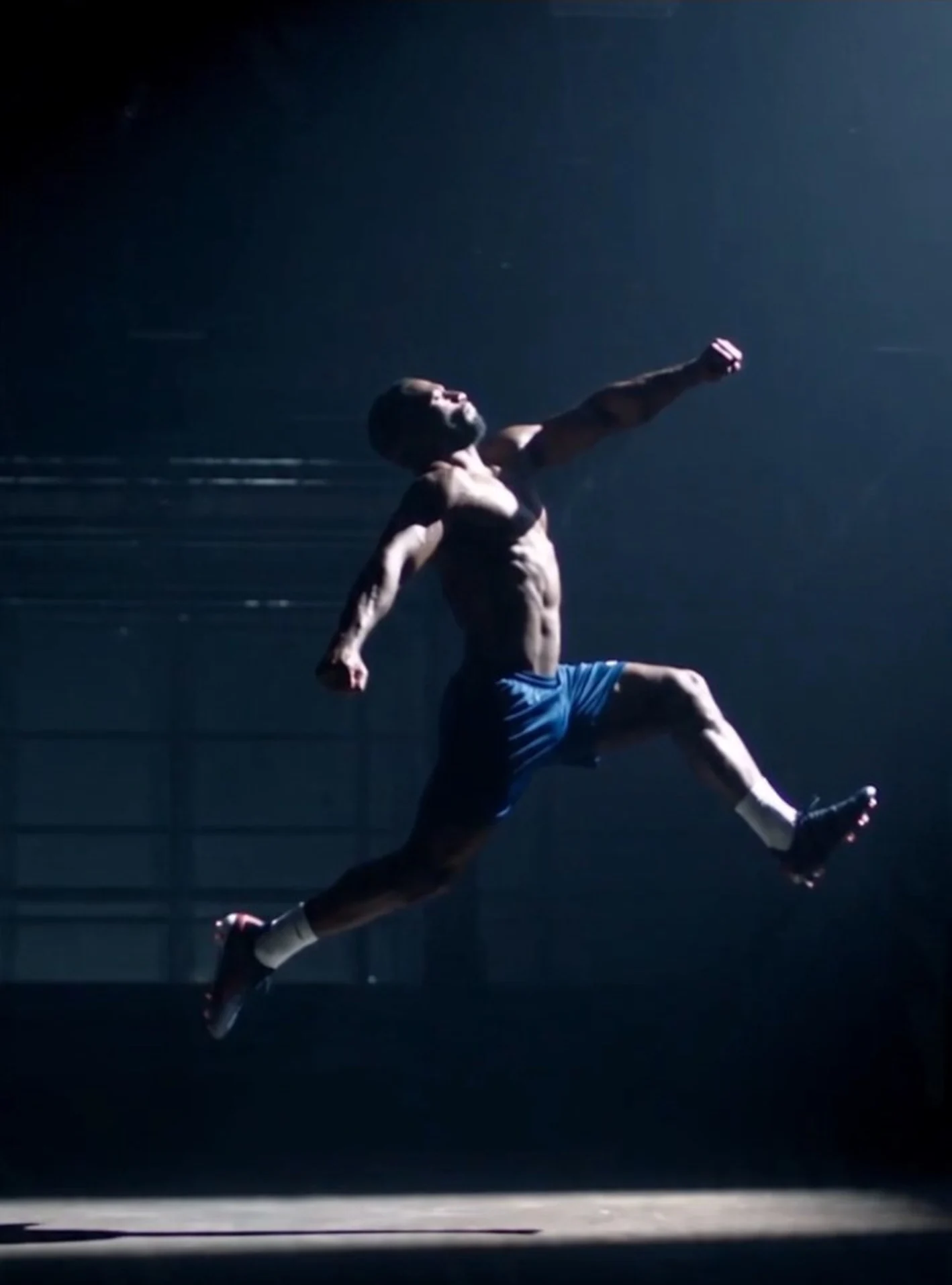 Male athlete in a powerful airborne training leap under a single cinematic light