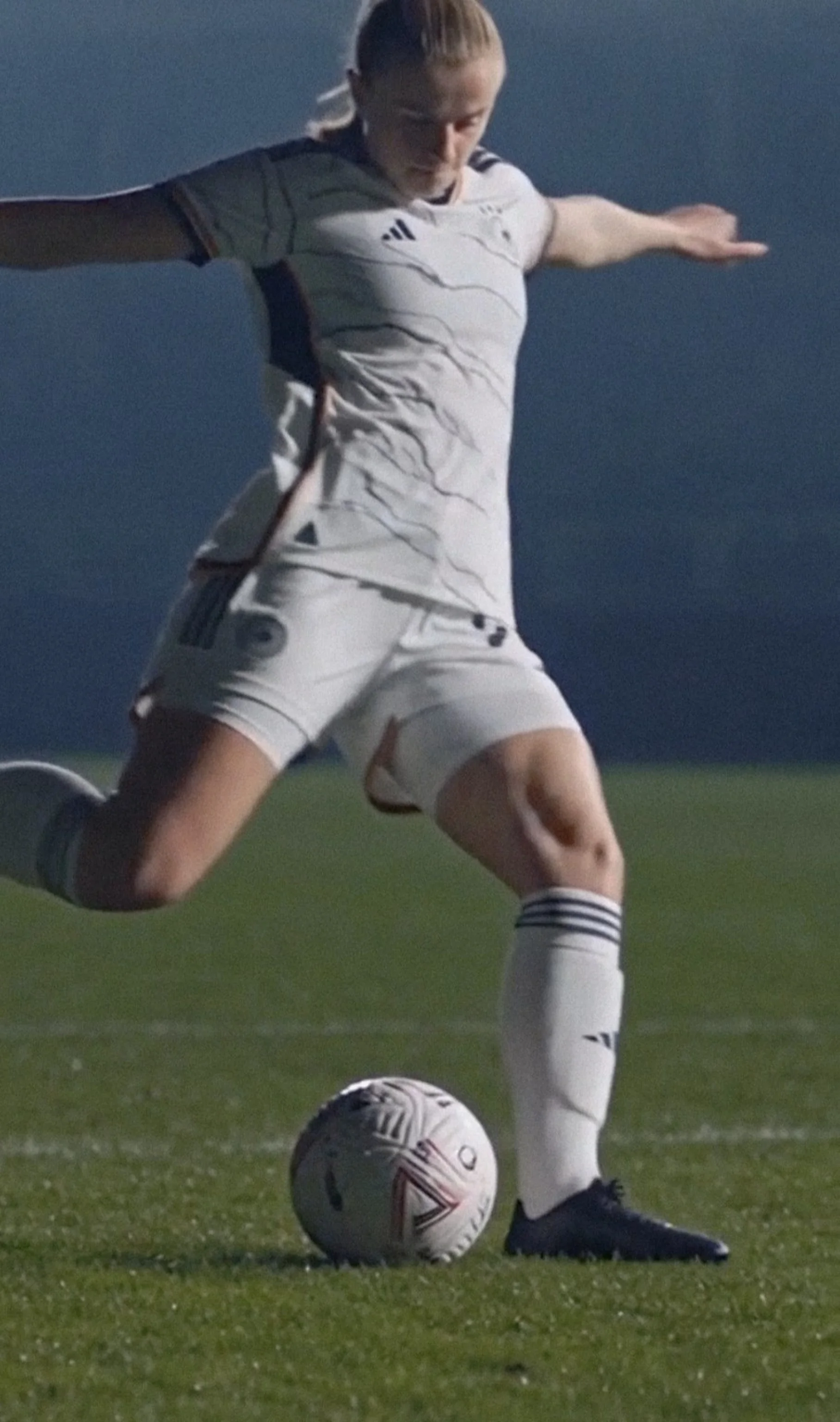 Women's football athlete striking a ball in competition